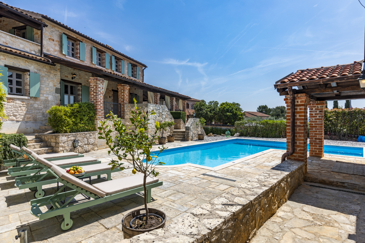 Eine traditionelle istrische Villa mit einer großen Außenterrasse mit beheiztem Pool, Sonnenliegen und einem Zitronenbaum.