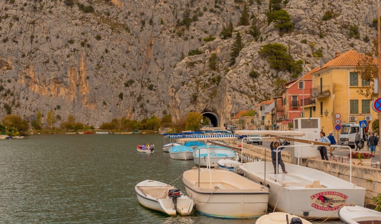 The town of Omiš with boats moored on the shore. At the end of the road, an impressive mountain looms over